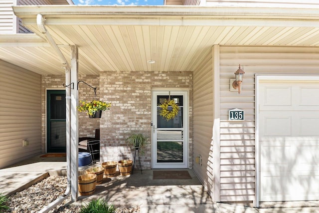 view of exterior entry featuring covered porch and brick siding