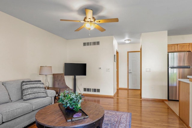 living area with a ceiling fan, light wood finished floors, and baseboards
