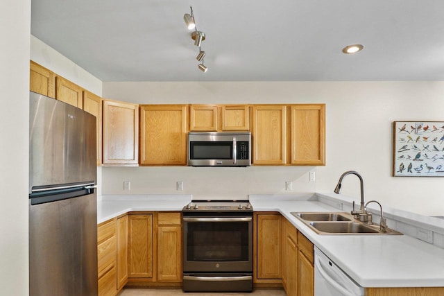 kitchen with stainless steel appliances, a sink, a peninsula, light countertops, and recessed lighting
