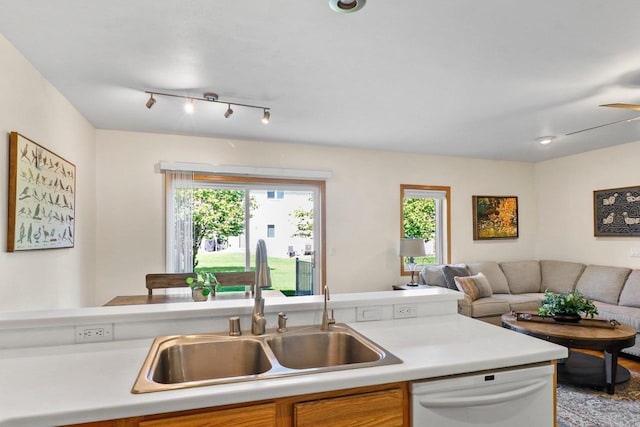 kitchen featuring dishwasher, a sink, light countertops, and open floor plan