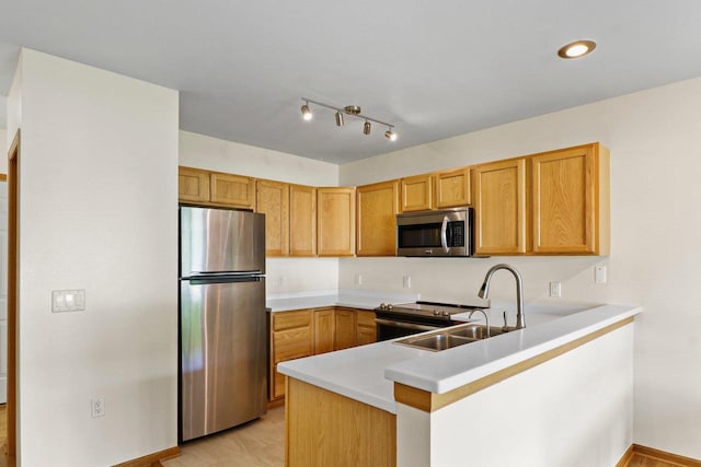 kitchen with stainless steel appliances, a sink, a peninsula, light countertops, and baseboards