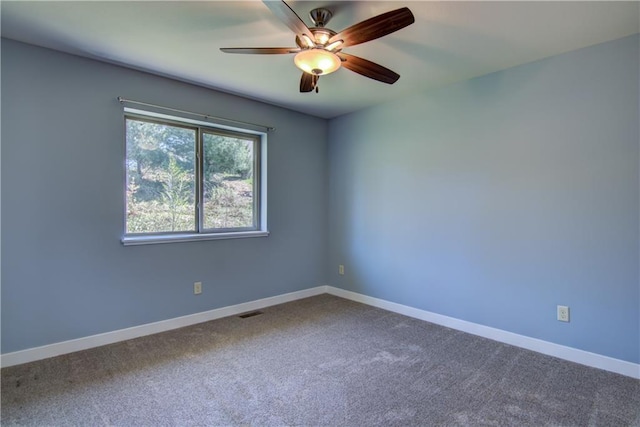 carpeted empty room with a ceiling fan and baseboards