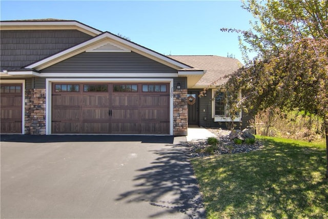 view of front of house with stone siding, an attached garage, driveway, and a front yard