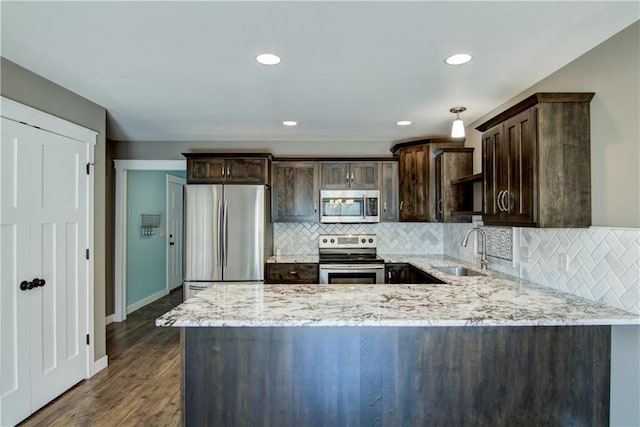 kitchen featuring appliances with stainless steel finishes, a sink, dark brown cabinetry, light stone countertops, and recessed lighting