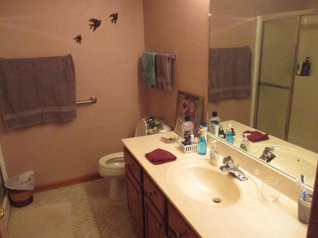 full bath with a stall shower, toilet, vanity, and baseboards