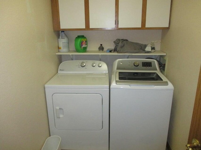 clothes washing area featuring cabinet space and washing machine and dryer