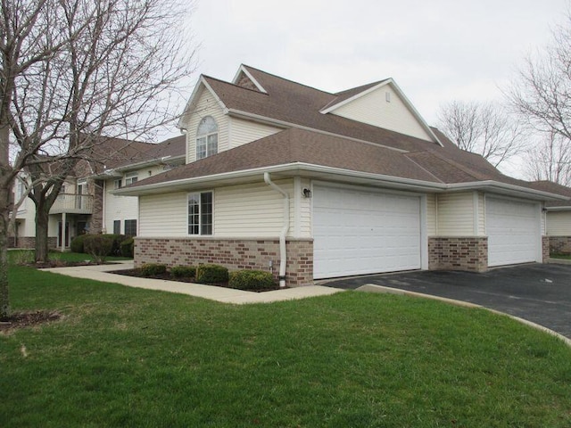 view of side of home featuring brick siding, driveway, an attached garage, and a yard