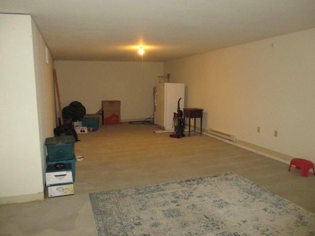 finished basement featuring freestanding refrigerator and a baseboard heating unit