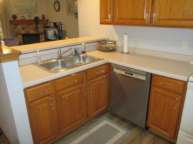 kitchen with stainless steel dishwasher, a sink, a peninsula, light countertops, and brown cabinetry
