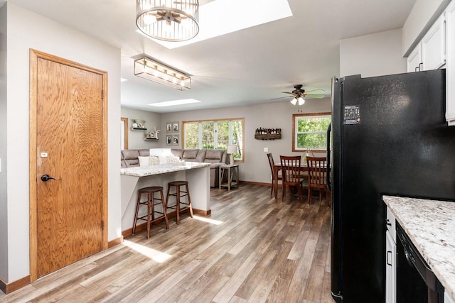 7929 N Pine View Dr, Edgerton, WI 53534 - kitchen featuring black appliances, light wood-style flooring, a ceiling fan, a kitchen bar, and baseboards