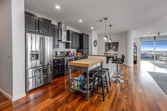 601 E Ogden Ave Unit 803, Milwaukee, WI 53202 - kitchen featuring stainless steel appliances, wall chimney exhaust hood, dark wood-style floors, recessed lighting, and light stone countertops