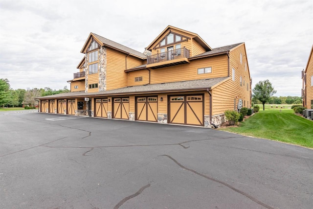 1822-3 Parkland Dr Unit 0703, Arkdale, WI 54613 - view of front of house with a balcony, a front yard, stone siding, central air condition unit, and community garages