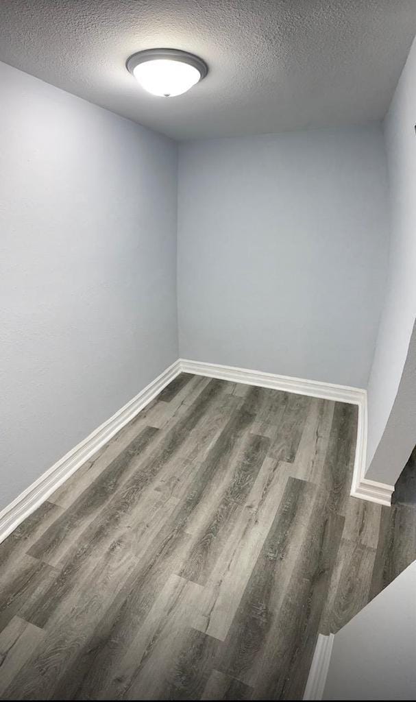 1952 S Wisconsin Ave, Beloit, WI 53511 - unfurnished room with a textured ceiling, dark wood-style floors, and baseboards