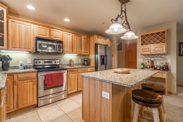 1839-6 20th Blvd Unit 0206, Arkdale, WI 54613 - kitchen featuring appliances with stainless steel finishes, a kitchen island, light tile patterned floors, light stone countertops, and a kitchen bar