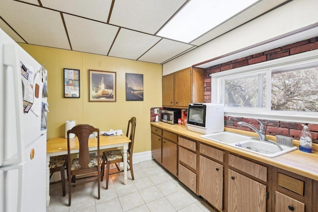 604 9th Ave, Baraboo, WI 53913 - kitchen featuring a sink, stainless steel microwave, light countertops, light tile patterned floors, and a paneled ceiling