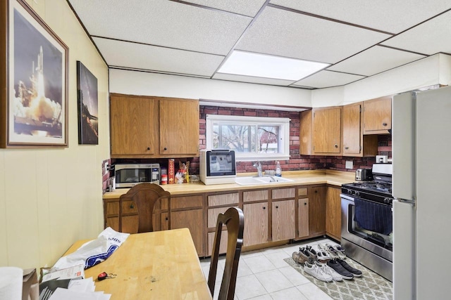 604 9th Ave, Baraboo, WI 53913 - kitchen with stainless steel appliances, a sink, light countertops, brown cabinetry, and a paneled ceiling