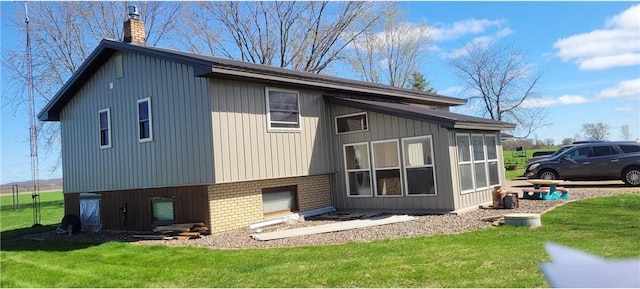 E7065 County Road B, Colfax, WI 54730 - back of house with a chimney, brick siding, a yard, and a sunroom