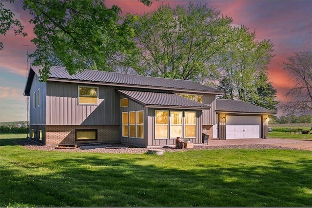 E7065 County Road B, Colfax, WI 54730 - back of property at dusk with a garage, driveway, a yard, and metal roof