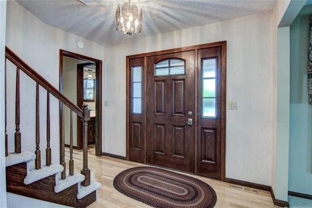 1206 Nixon Ave, Eau Claire, WI 54701 - entryway featuring stairs, light wood-type flooring, baseboards, a chandelier, and a textured ceiling
