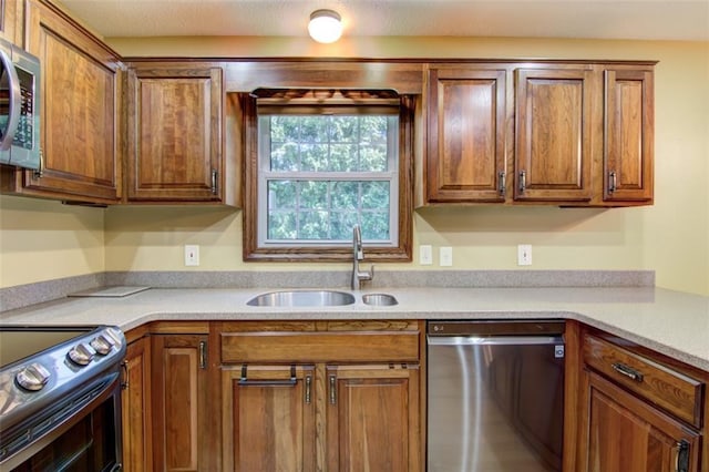 1206 Nixon Ave, Eau Claire, WI 54701 - kitchen with stainless steel appliances, a sink, brown cabinetry, and light countertops
