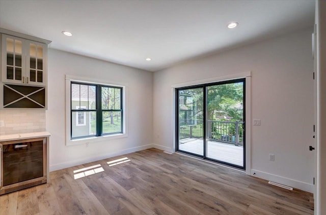 713 Kennedy St, Sauk City, WI 53583 - unfurnished living room with wine cooler, baseboards, light wood finished floors, and recessed lighting