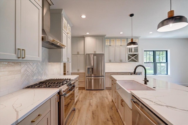 713 Kennedy St, Sauk City, WI 53583 - kitchen with appliances with stainless steel finishes, a sink, light wood-style flooring, wall chimney range hood, and glass insert cabinets
