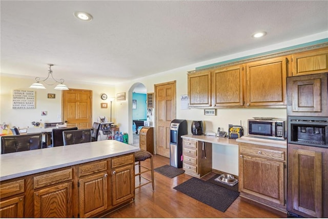 2136 62nd St, Somerset, WI 54025 - kitchen with stainless steel microwave, arched walkways, light countertops, dark wood-type flooring, and brown cabinetry