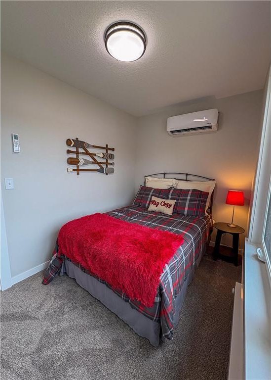 11445 State Highway 48, Luck, WI 54853 - carpeted bedroom with a wall mounted air conditioner, a textured ceiling, and baseboards