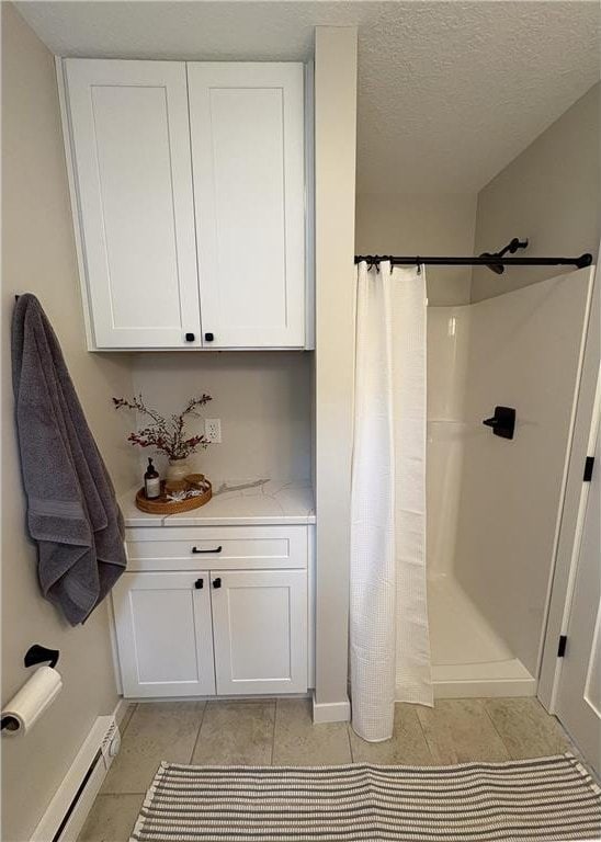11445 State Highway 48, Luck, WI 54853 - full bathroom featuring a shower with shower curtain, baseboards, tile patterned floors, baseboard heating, and a textured ceiling