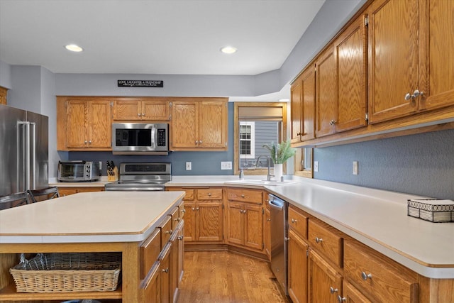 W127S9630 Scott Krause Dr, Muskego, WI 53150 - kitchen featuring appliances with stainless steel finishes, a sink, light countertops, light wood-style floors, and brown cabinetry
