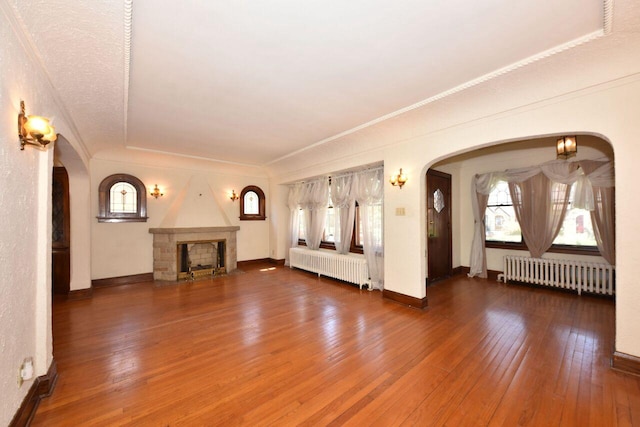 3434 N 45th St, Milwaukee, WI 53216 - unfurnished living room with radiator, wood-type flooring, arched walkways, a fireplace, and ornamental molding