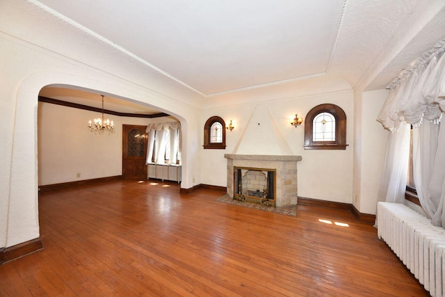 3434 N 45th St, Milwaukee, WI 53216 - unfurnished living room with radiator heating unit, a chandelier, a large fireplace, arched walkways, and crown molding