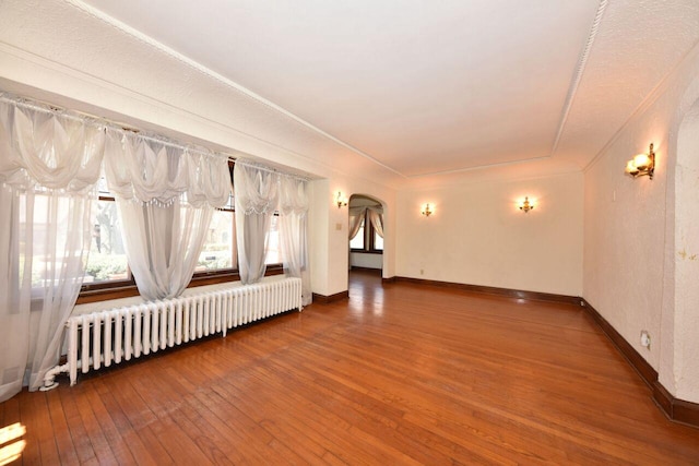 3434 N 45th St, Milwaukee, WI 53216 - unfurnished living room with radiator heating unit, hardwood / wood-style floors, arched walkways, baseboards, and ornamental molding