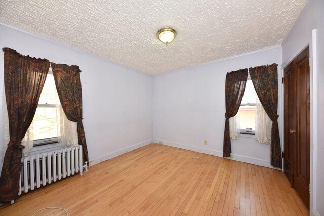 3434 N 45th St, Milwaukee, WI 53216 - empty room featuring radiator, a textured ceiling, wood-type flooring, and baseboards
