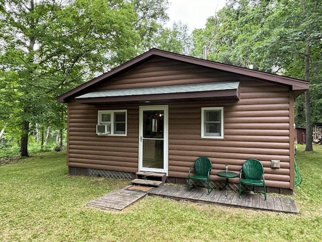 rear view of house featuring faux log siding, a lawn, and a wooden deck