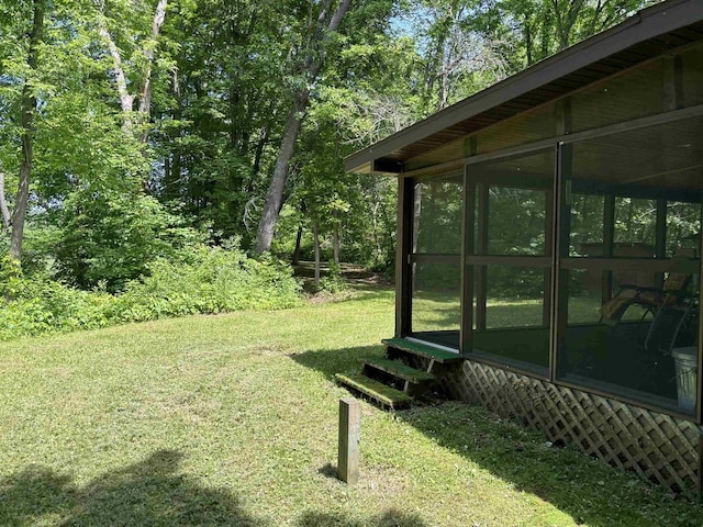 view of green lawn featuring a sunroom
