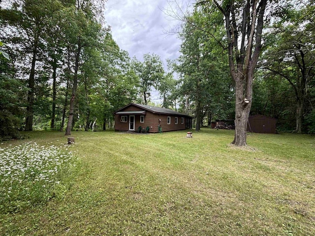 view of grassy yard with a storage unit and an outbuilding