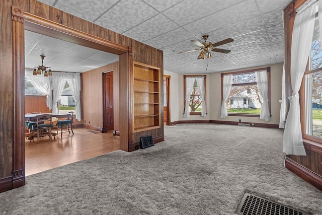 290 S Bridge St, Markesan, WI 53946 - carpeted living room with baseboards, a ceiling fan, wood walls, and a drop ceiling