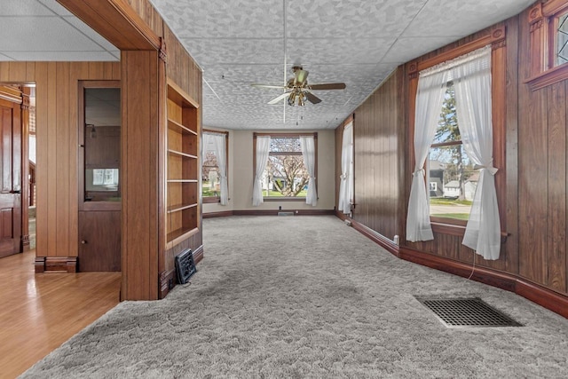 290 S Bridge St, Markesan, WI 53946 - unfurnished living room with a ceiling fan, wooden walls, and carpet floors