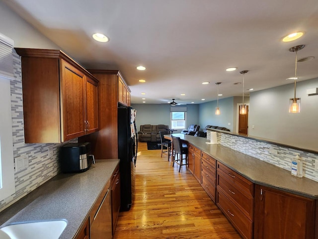 1120 W Blackhawk Dr, Fort Atkinson, WI 53538 - kitchen with black fridge with ice dispenser, a ceiling fan, open floor plan, light wood finished floors, and backsplash