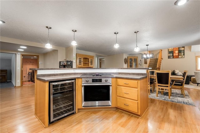 kitchen featuring wine cooler, oven, black electric cooktop, open floor plan, and light wood-style flooring