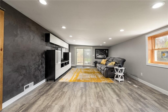 living room with baseboards, wood finished floors, and recessed lighting