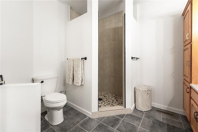 bathroom with tile patterned flooring, a shower stall, baseboards, and toilet