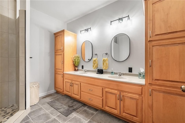 bathroom featuring a tile shower, double vanity, and tile patterned flooring