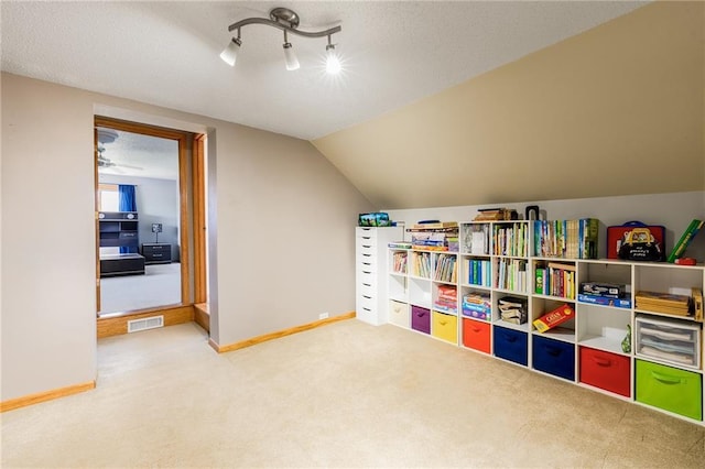 game room featuring carpet flooring, baseboards, rail lighting, a textured ceiling, and vaulted ceiling