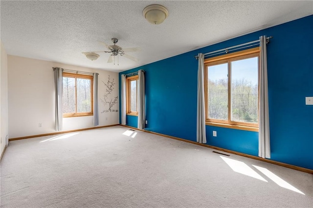 spare room with carpet flooring, baseboards, a textured ceiling, and a ceiling fan
