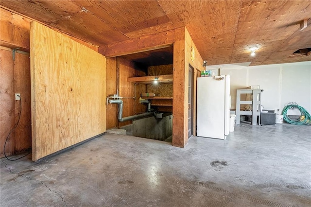 below grade area featuring freestanding refrigerator and wooden ceiling