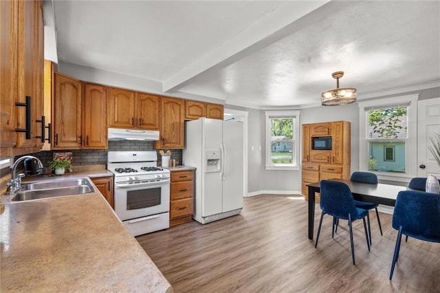 119 E 1st St, Dresser, WI 54009 - kitchen featuring white appliances, under cabinet range hood, a sink, brown cabinets, and decorative backsplash