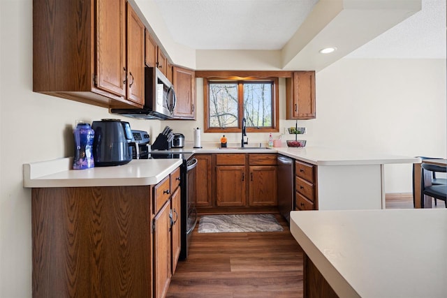840 Waterworks Rd, Nekoosa, WI 54457 - kitchen featuring a sink, stainless steel appliances, a peninsula, dark wood-style floors, and brown cabinetry