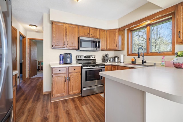 840 Waterworks Rd, Nekoosa, WI 54457 - kitchen with stainless steel appliances, a sink, light countertops, and dark wood finished floors